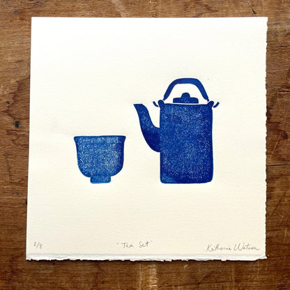 A block print of a teapot and cup in navy ink